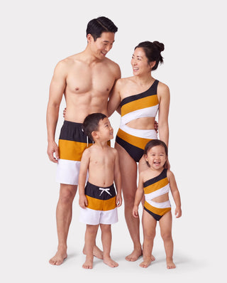 Family matching colourblock swim trunks and a one-shoulder one-piece, one print carried across two different cuts