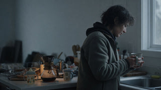 Parent standing alone in a quiet kitchen at 5 a.m. in pre-dawn light
