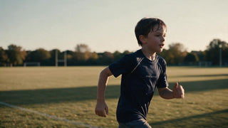Boy running across a grass pitch in a lightweight quick-dry sports top at golden hour
