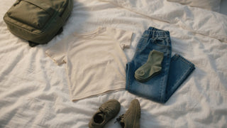 Easy-care kids' school clothes laid out the night before on a bed — pull-on pants, a soft tee, and socks ready for a busy morning