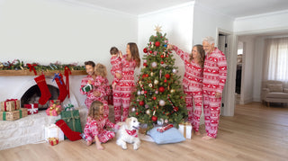 A family of five and their dog in matching gingerbread print Christmas pajamas on the living room floor