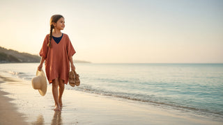 School-age girl in a loose cotton cover-up over her swimsuit walking along the beach at golden hour
