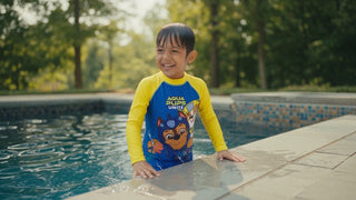 Child in a quick-dry swimsuit climbing out of a pool on a bright summer day
