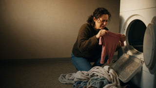 Parent removing a shrunken damaged garment from a tumble dryer