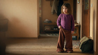 Young child in trousers that are too big, hems dragging and waistband slipping