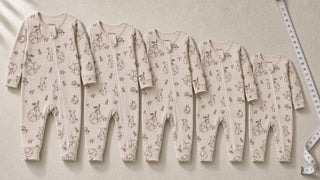 Five PatPat baby pajamas laid out in size order from Newborn to 18M beside a tape measure