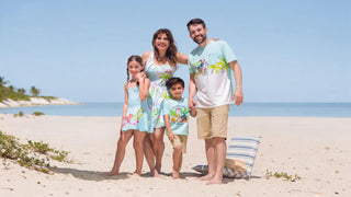 Family of four in coordinated cream, navy and terracotta resort wear walking on a beach at golden hour
