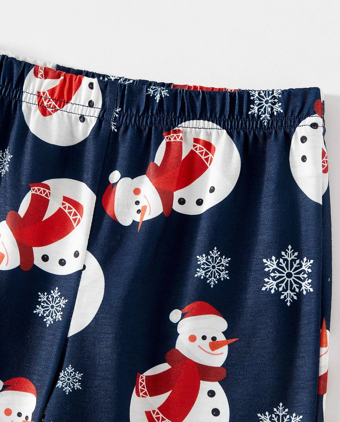 Pijamas familiares a juego con estampado de letras y muñeco de nieve navideño, mangas raglán y calcetines navideños en bloques de color.