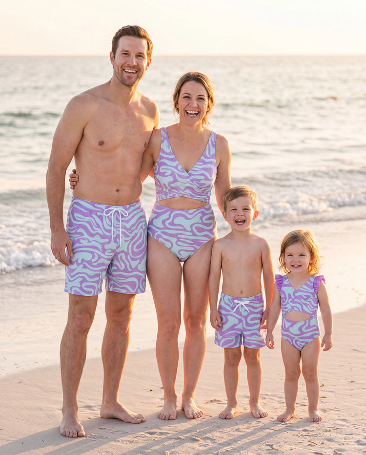 Familienpassende, trendige Badehose mit lila und blauem Wellendruck oder einteiliger Badeanzug mit Taillenausschnitt lila